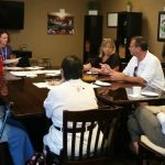 Photo of Kathleen Kenney speaking to the group gathered around a conference table