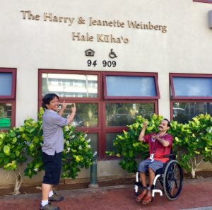 Photo of Thomas and Rene in front of Hale Kuhao sign