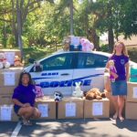 Photo of staff next to police car with boxes of stuffed animals