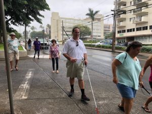 Photo of Brian walking using a white cane