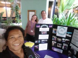 Photo of Lani, Kathleen, and Brian standing by AILH booth