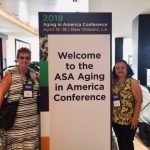 Photo of Sam and Roxanne standing next to sign that reads "Welcome tot he ASA Aging in America Conference"