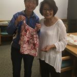 Photo of Florence Tseng and Iris Kaneshiro holding newly finished sewing project